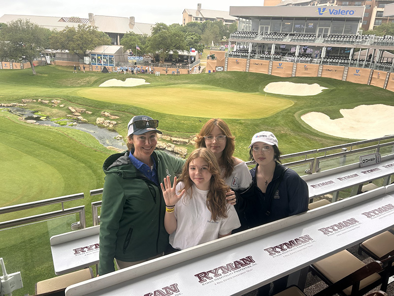 Andi Meadows and her three children in the stands at a golf course